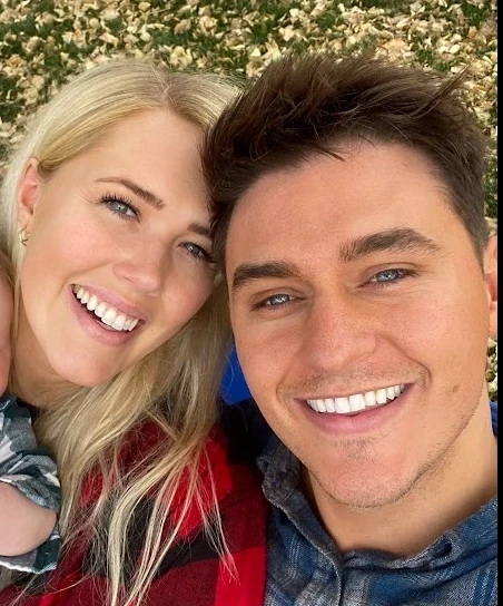 Selfie of Will Wright and Will’s wife smiling outdoors, autumn leaves on the grass behind them
